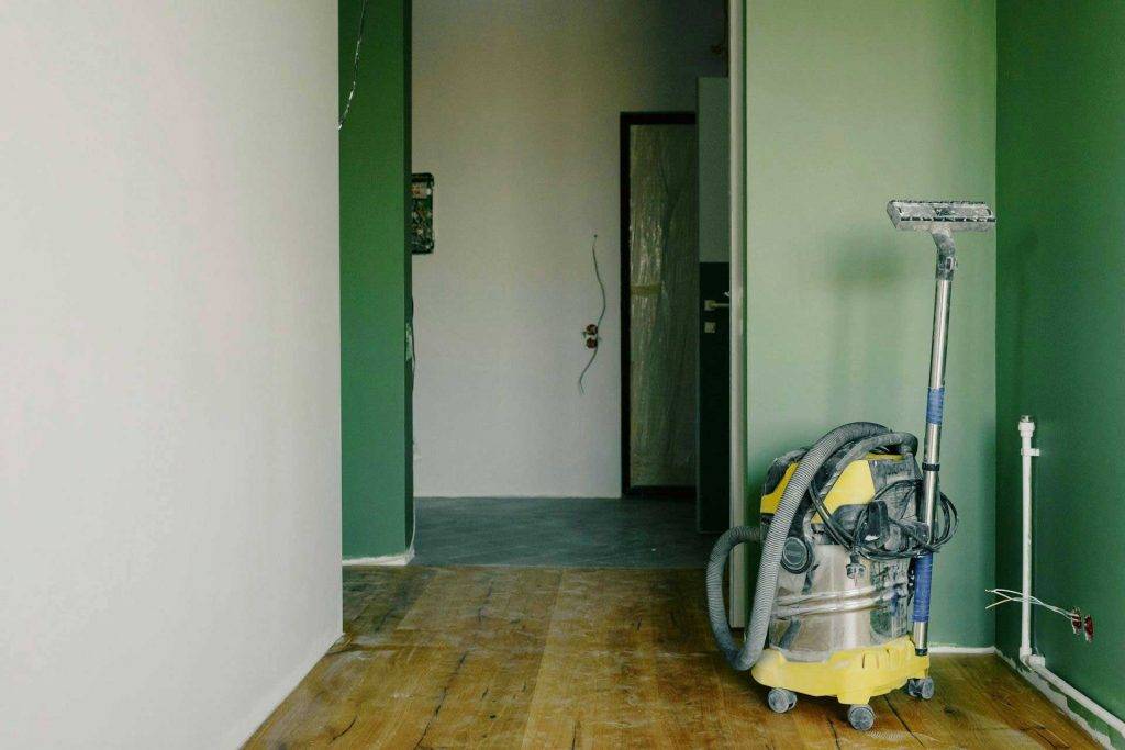 Gelber Industriestaubsauger von Reinigungskonzepte Berlin befindet sich in einem renovierten Raum mit grünen Wänden.
