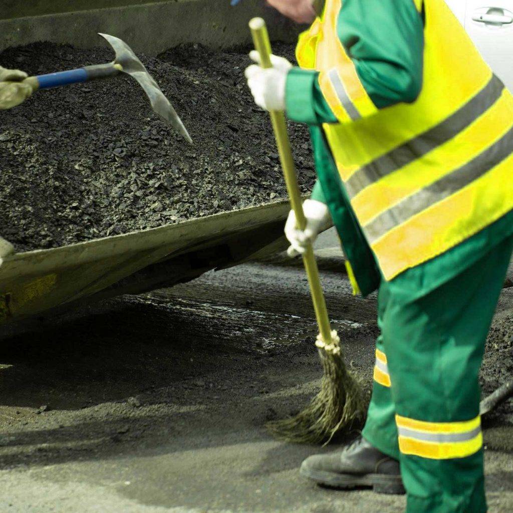 Mitarbeiter von Reinigungskonzepte Bornheim schaufeln auf einer Baustelle Schutt & Abfall in eine Industrieschubkarre.
