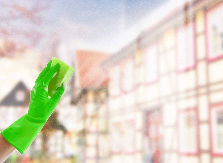 Es ist unscharf die Stadt Riesa zu sehen. Im Vordergrund reinigt ein Mitarbeiter von Reinigungskonzepte ein Fenster.