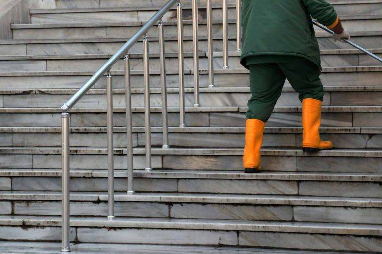 Ein Mitarbeiter von Reinigungskonzepte Wesel säubert die Treppe eines Kunden mit einem Besen.