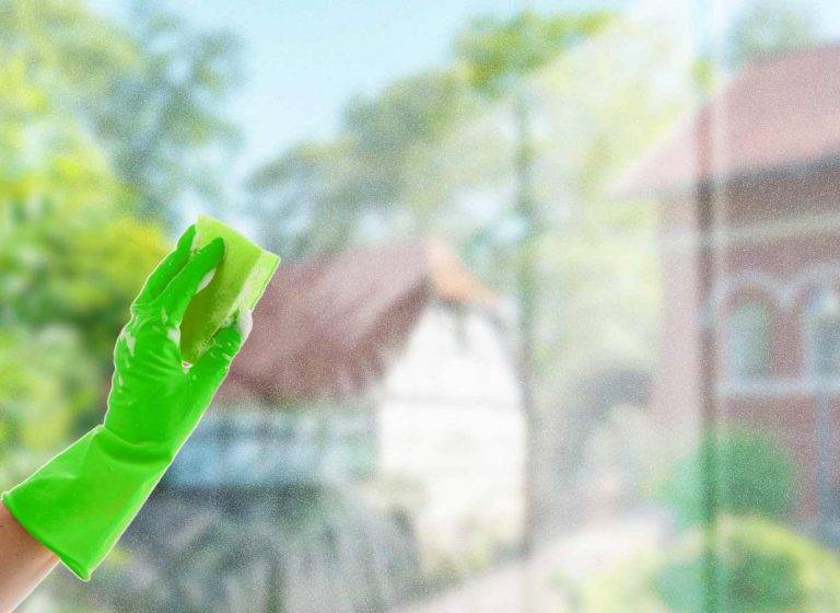 Ein Mitarbeiter von Reinigungskonzepte reinigt eine Fensterscheibe – im Hintergrund ist unscharf die Stadt Dinslaken zu sehen.