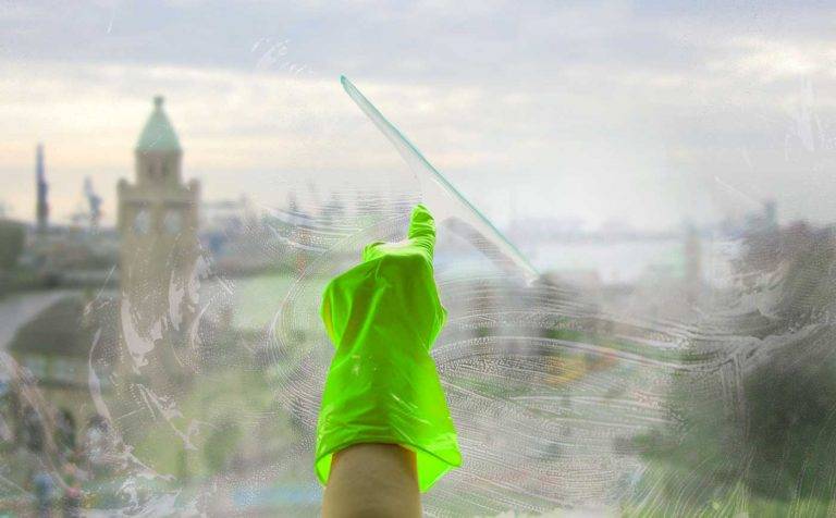 Fensterputz durch einen Mitarbeiter von Reinigungskonzepte mit einem Glasabzieher: im Hintergrund erkennt man Hamburg.
