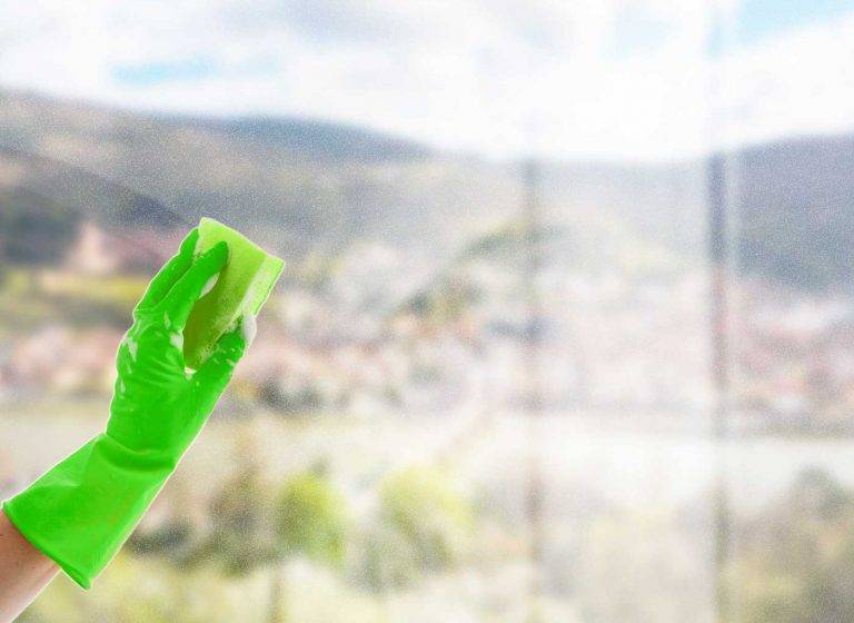Ein Mitarbeiter von Reinigungskonzepte putzt die Glasscheibe eines Kunden. Im Hintergrund kann man Heidelberg erkennen.