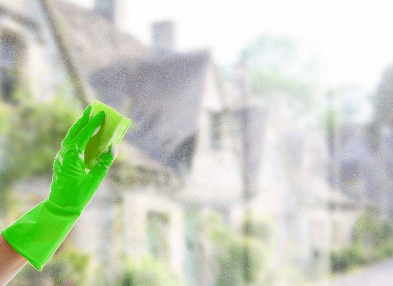 Ein Mitarbeiter von Reinigungskonzepte reinigt die Fensterscheibe eines Kunden. Im Hintergrund kann man Hünxe erkennen.