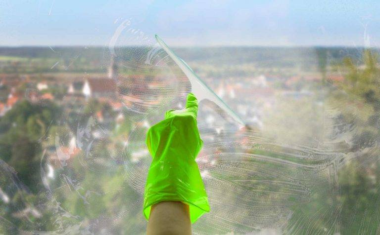 Ein Mitarbeiter von Reinigungskonzepte säubert eine Fensterscheibe, im Hintergrund kann man die Stadt Strausberg erkennen.